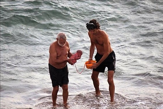 Foto del bambino in braccio al dottore, dentro al Mar Rosso
